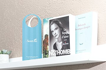 Three books on a shelf including one by nothomb