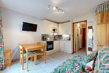 A kitchen with a table and chairs and a flat screen tv