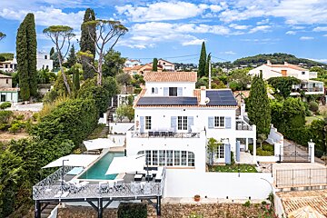 A large white house with solar panels on the roof