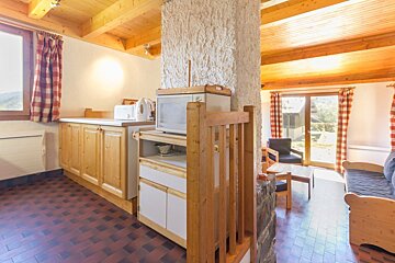 A kitchen with a microwave on top of a shelf