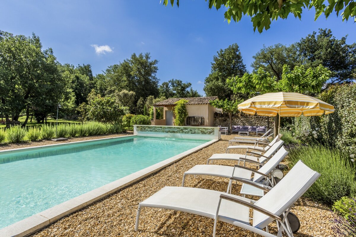 A yellow and white umbrella sits in front of a swimming pool