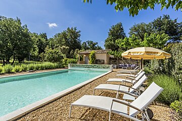 A yellow and white umbrella sits in front of a swimming pool