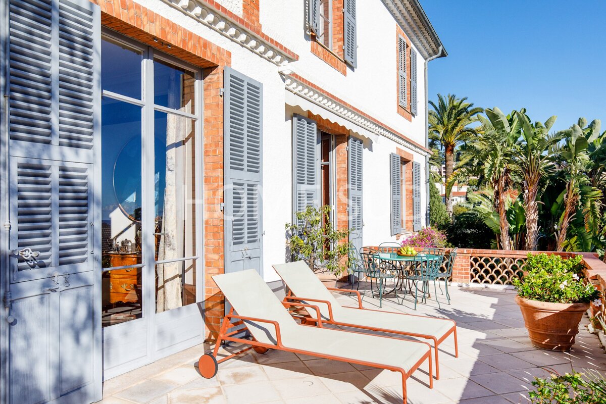 Two lounge chairs sit on a patio in front of a brick building