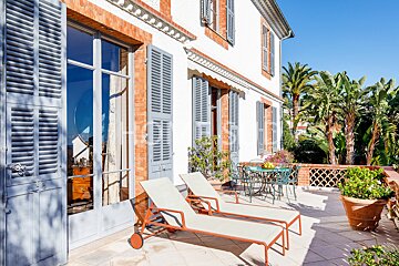 Two lounge chairs sit on a patio in front of a brick building