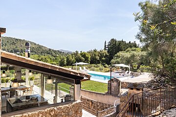 A large swimming pool is surrounded by trees and mountains