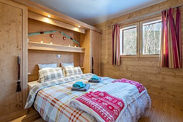 A wooden bedroom with a bed and a window