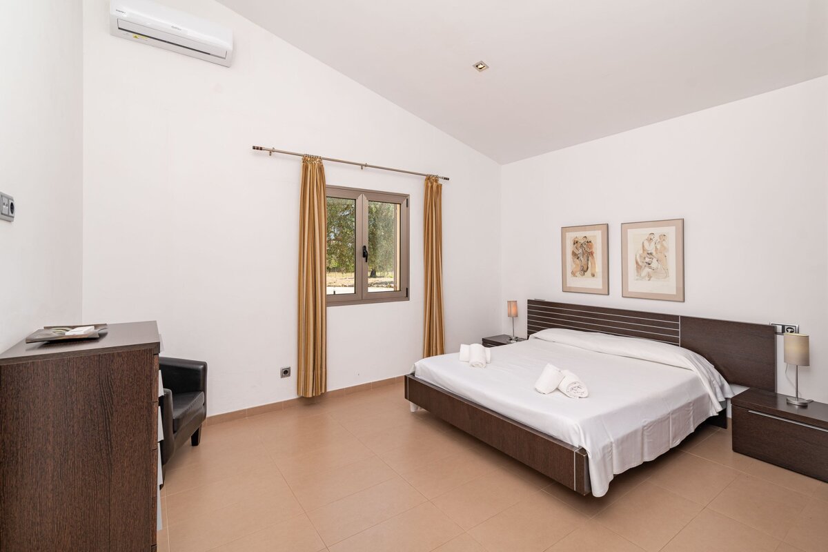 A bedroom with a large bed and two paintings on the wall