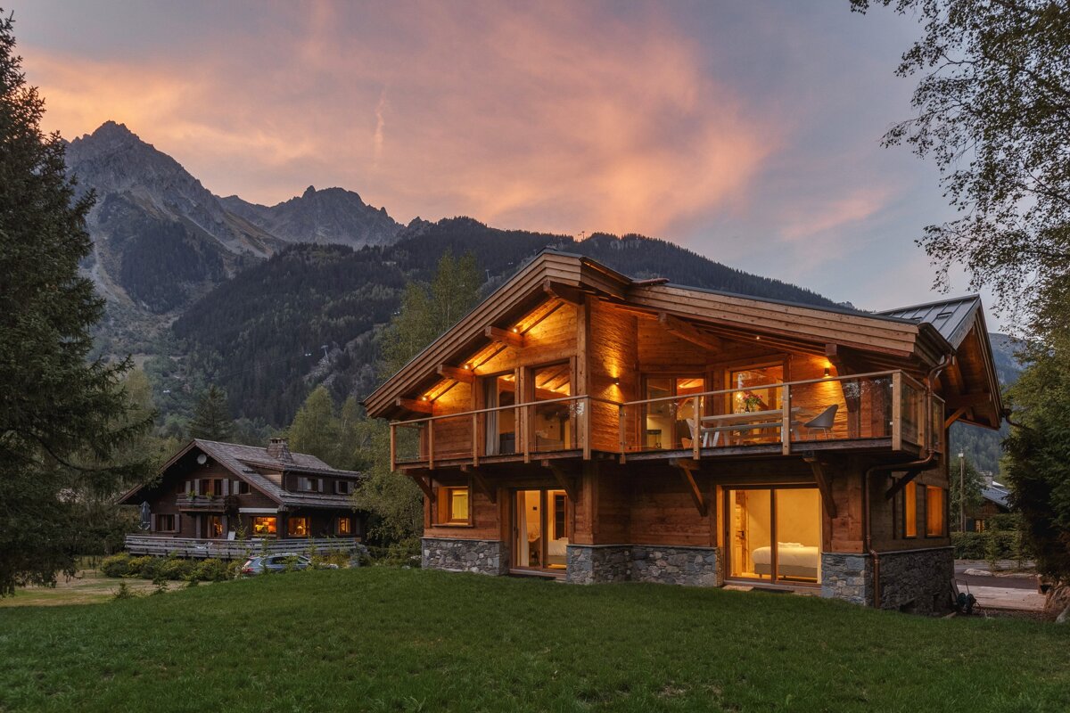 A large wooden house with mountains in the background