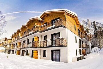 A building with a lot of windows and balconies is covered in snow