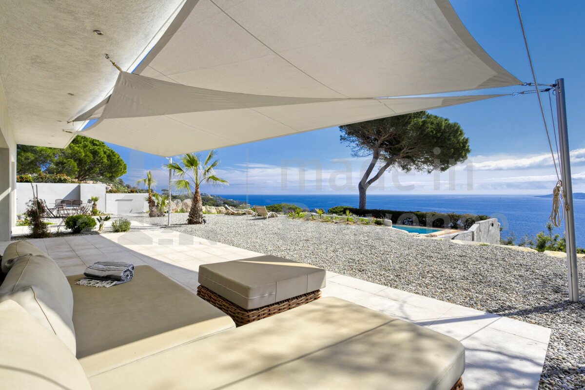A view of the ocean from a patio with a white umbrella