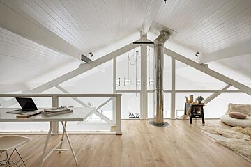 A white desk with a laptop on it in a room with a vaulted ceiling