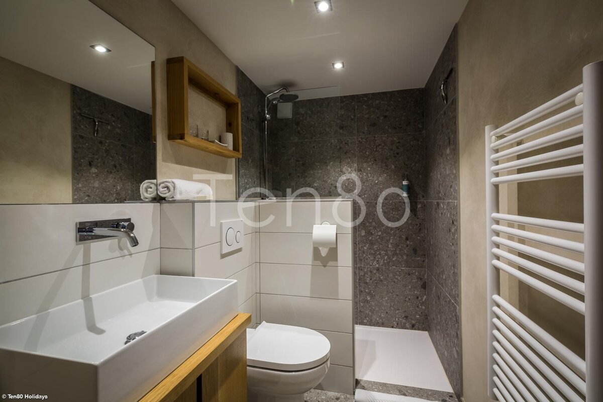 A bathroom with a toilet and a sink with the word ten80 on the wall