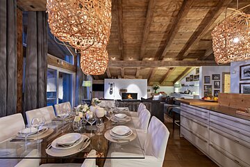 A dining room with a glass table and white chairs