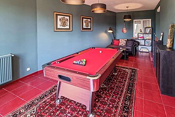 A pool table in a room with a red rug