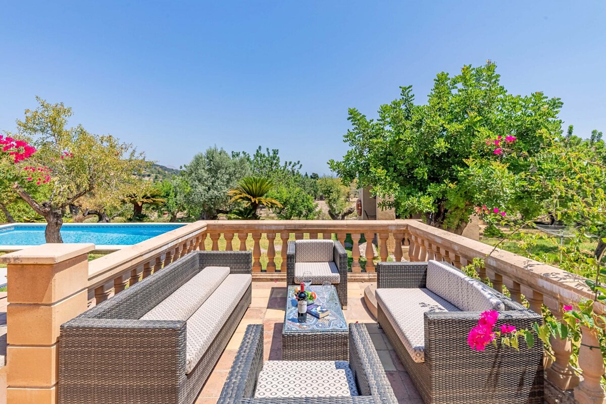 A patio with wicker furniture and a table with flowers on it
