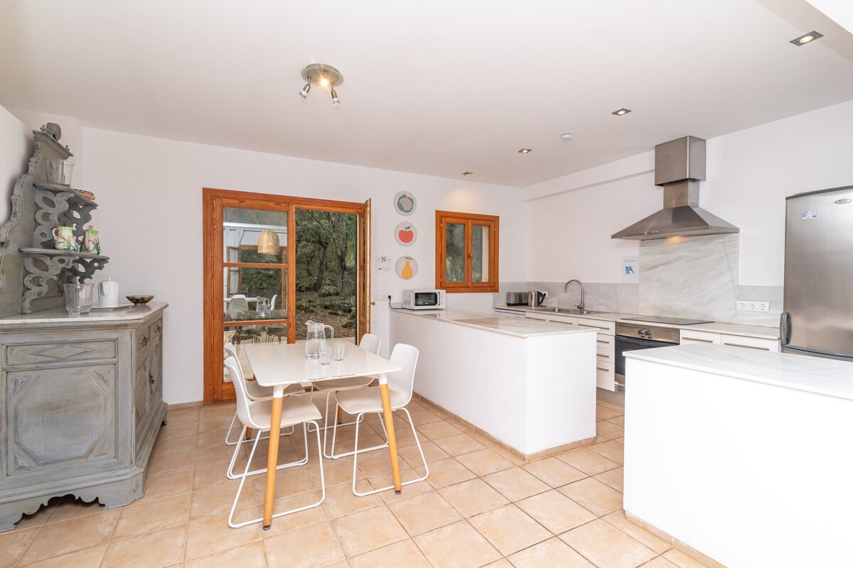 A kitchen with a table and chairs and a stainless steel refrigerator