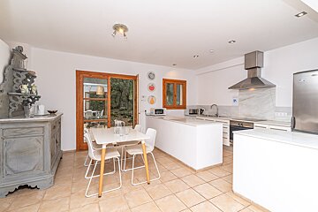 A kitchen with a table and chairs and a stainless steel refrigerator