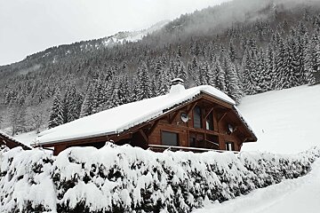 A snowy house with a mountain in the background