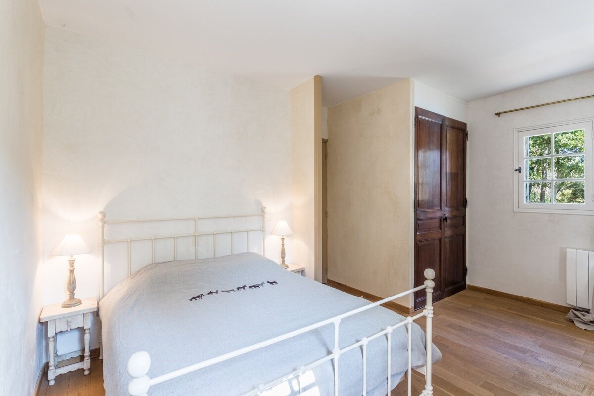 A bedroom with a white bed and a window