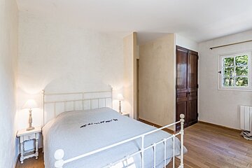 A bedroom with a white bed and a window