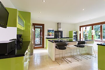 A kitchen with green cabinets and black counter tops