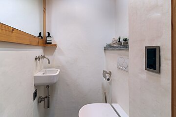 A bathroom with a sink and toilet and a bottle of aesop