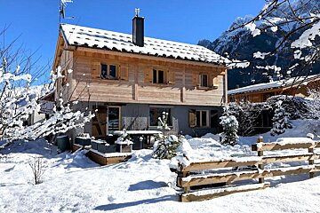 A snowy house with a fence in front of it