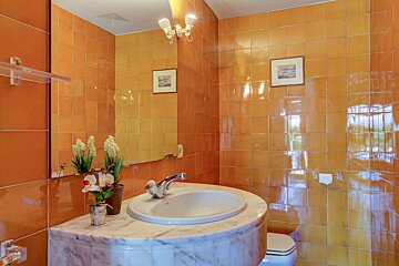 A bathroom with orange tiles and a sink and toilet