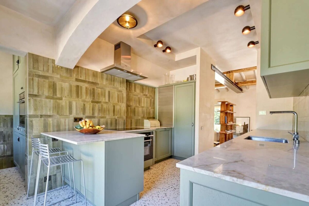 A kitchen with green cabinets and white counter tops