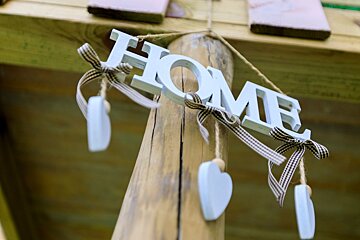 The word home is hanging from a wooden pole