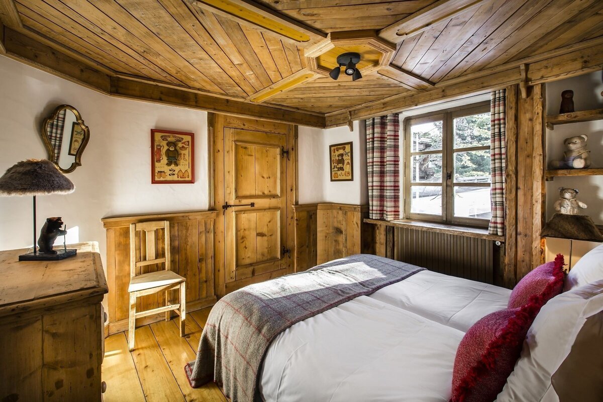 A bedroom with a wooden ceiling and a bed