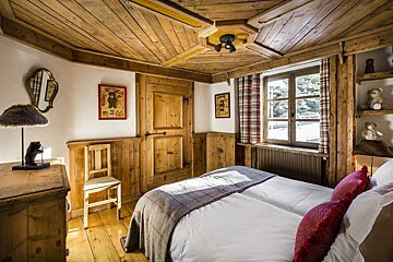 A bedroom with a wooden ceiling and a bed