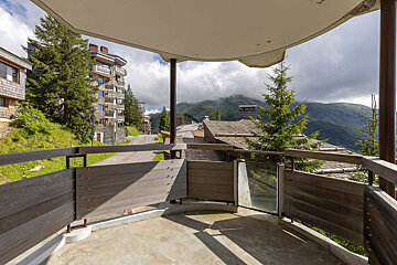 A balcony with a view of mountains and trees