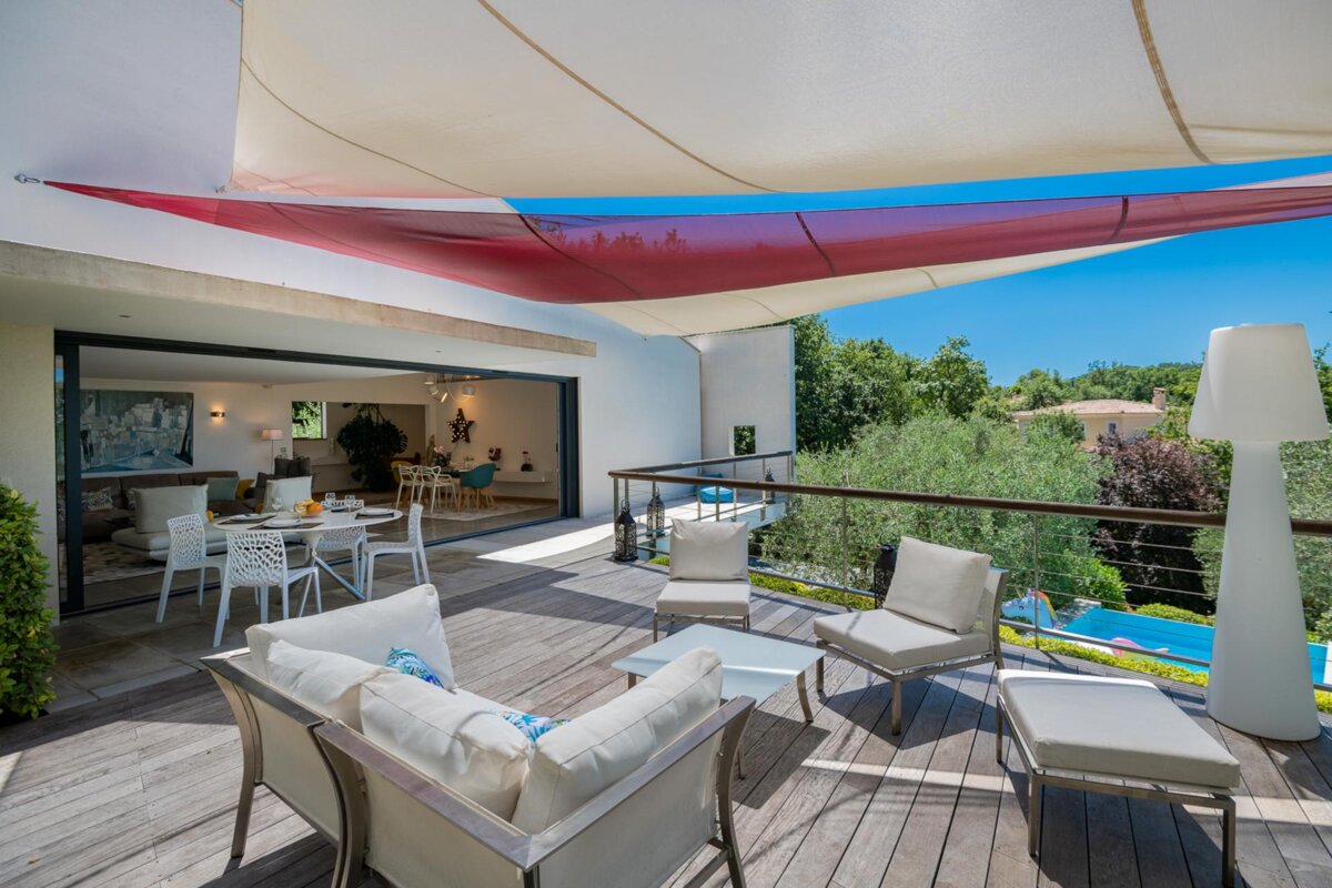 A deck with a couch and chairs under a canopy