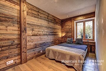 A bedroom with wood paneled walls and a bed that says mountain base