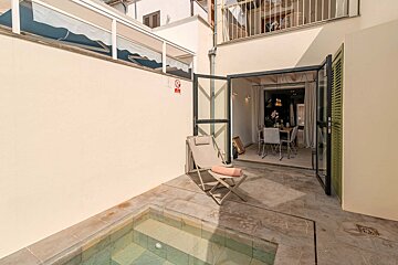 A chair sits in front of a swimming pool with a no swimming sign on the wall