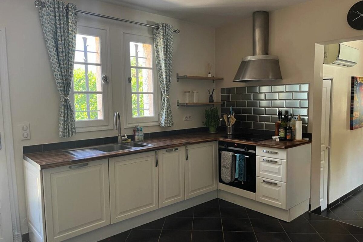 A kitchen with white cabinets and black tiles