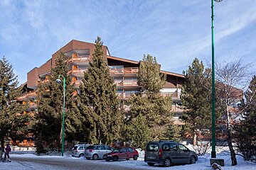 A building with a lot of balconies and cars parked in front of it