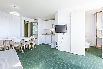 A living room with a table and chairs and a flat screen tv