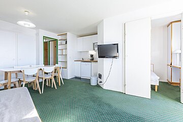 A living room with a table and chairs and a flat screen tv