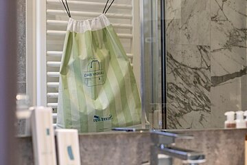 A green and white striped bag hanging on a towel rack