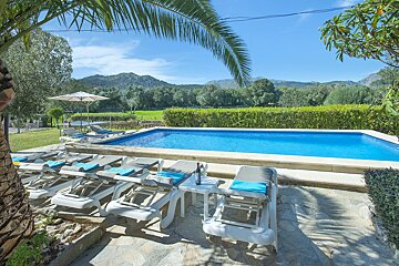 A bottle of wine sits on a table next to a swimming pool