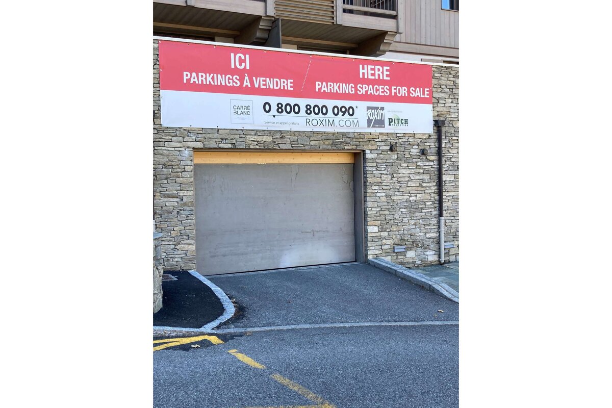 A sign on the side of a building that says here parking spaces for sale