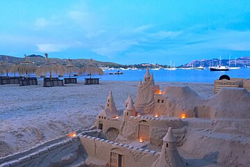 A sand castle on a beach with boats in the background