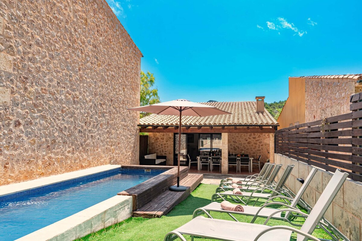 A swimming pool is surrounded by lawn chairs and an umbrella