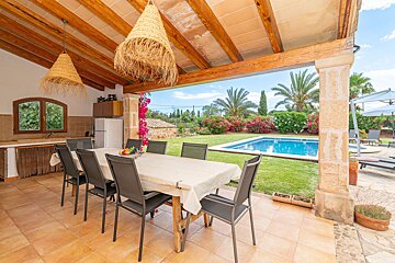 A patio with a table and chairs overlooking a swimming pool