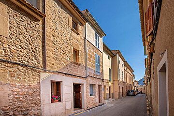 A narrow street with a stone building on the right