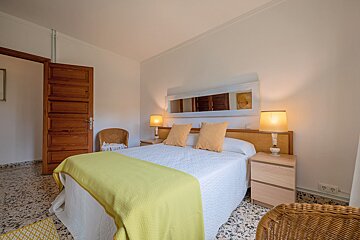 A bedroom with a yellow blanket on the bed