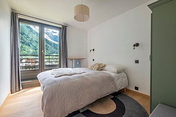 A bedroom with a bed and a window with mountains in the background