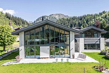 A house with a lot of windows and a mountain in the background